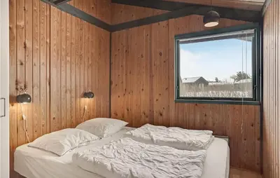 a bedroom with a bed in a wooden wall at 3 Bedroom Stunning Home In Blokhus in Blokhus