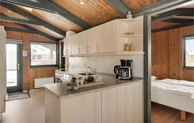a kitchen with white cabinets and a bed in a room at 3 Bedroom Stunning Home In Blokhus in Blokhus