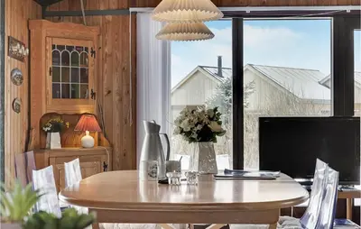 a dining room with a table and a large window at 3 Bedroom Stunning Home In Blokhus in Blokhus