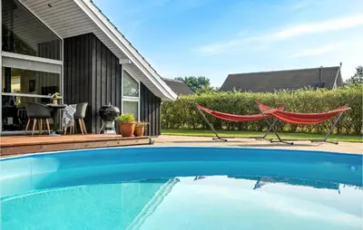 a swimming pool with two hammocks and a house at Gorgeous Home In Vemb in Vemb