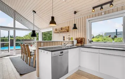 a kitchen with white cabinets and a table with chairs at Gorgeous Home In Vemb in Vemb