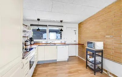 a kitchen with white cabinets and a brick wall at Cozy Home In Vesløs With House Sea View in Øsløs