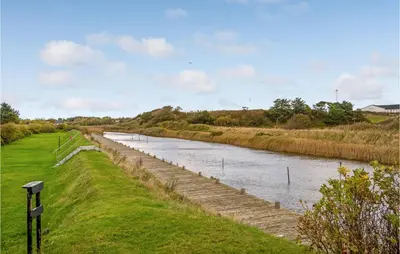 a river with a bridge next to a field at Gorgeous Home In Vestervig With Kitchen in Vestervig