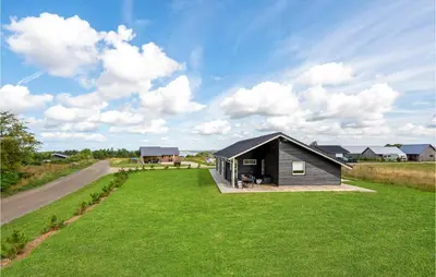 a small black house on a green field with a road at Beautiful Home In Løgstrup With Kitchen in Løgstrup