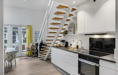 a kitchen with white cabinets and a spiral staircase at Agger Havn Feriecenter in Vestervig