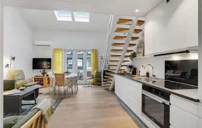 a kitchen with white cabinets and a living room at Agger Havn Feriecenter in Vestervig