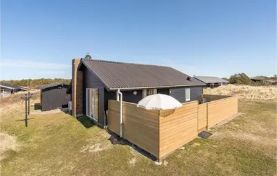 a house with a wooden deck in a field at Lovely Home In Thisted With Wifi in Thisted