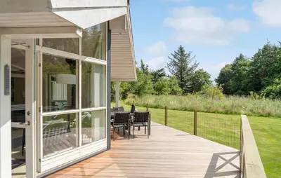 a house with a deck with a table and chairs at Lovely Home In Bedsted Thy With Sauna in Bedsted Thy