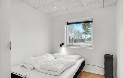 a white room with a bed with a window at Nice Home In Blokhus With Sauna in Blokhus