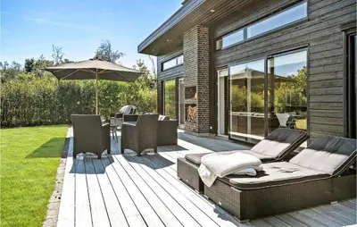 a wooden deck with chairs and an umbrella at Awesome Home In Thyholm With Wifi in Thyholm