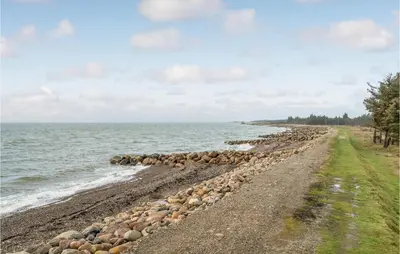 a rocky beach with a gravel road next to the water at 3 Bedroom Lovely Home In Hurup Thy in Sønder Ydby