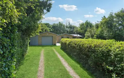 a hedge in front of a house with a garage at 3 Bedroom Lovely Home In Hurup Thy in Sønder Ydby