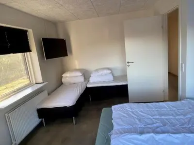 a bedroom with two beds and a window and a tv at Hytten in Lemvig