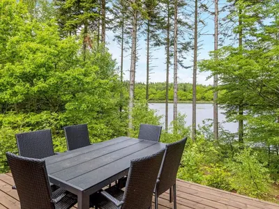 a wooden table and chairs on a deck with a view of a lake at 4 person holiday home in Aars-By Traum in Års