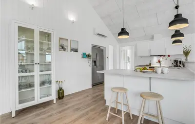 a kitchen with white cabinets and two stools at Amazing Home In Harboøre With 4 Bedrooms, Sauna & Wifi in Harboør