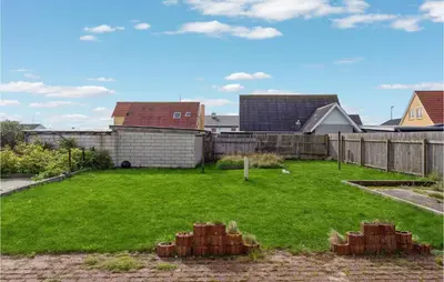 a backyard with a green yard with a fence at Lovely Home In Thyborøn With Kitchen in Thyborøn