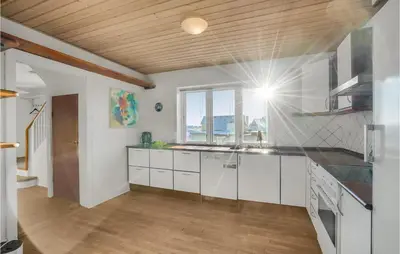 a kitchen with white cabinets and a wooden ceiling at Lovely Home In Thyborøn With Kitchen in Thyborøn