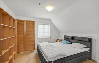 a bedroom with a large bed and wooden shelves at Lovely Home In Thyborøn With Kitchen in Thyborøn