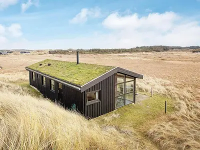 a small house with grass on the roof in a field at 6 person holiday home in Pandrup-By Traum in Pandrup