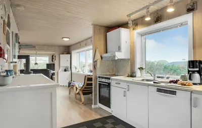 a kitchen with white cabinets and a large window at Stunning Home In Løkken With Kitchen in Løkken