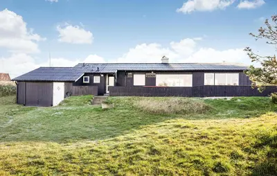a house with a black roof on a green field at Stunning Home In Løkken With Kitchen in Løkken