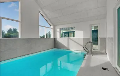 a swimming pool with blue water in a house with windows at Gorgeous Home In Blokhus With Jacuzzi in Blokhus