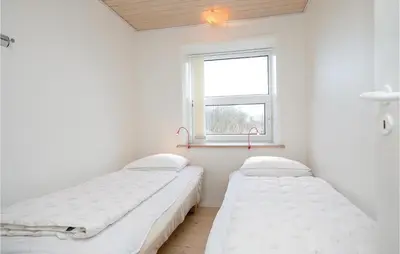 two beds in a room with a window at Holiday Home Egebækvej in Blokhus