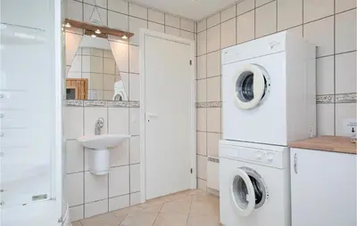 a bathroom with a washer and dryer and a sink at Holiday Home Egebækvej in Blokhus