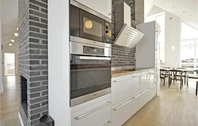 a kitchen with white cabinets and a brick wall at Holiday Home Ved Stranden in Blokhus