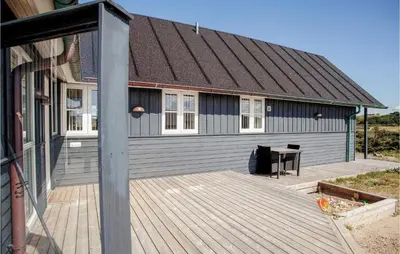 a house with a wooden deck in front of it at Holiday Home Ved Stranden in Blokhus
