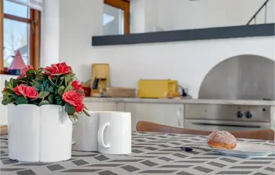 a table with two white coffee mugs and flowers on it at Holiday Home Strandlyst Vinderup Iv in Vinderup