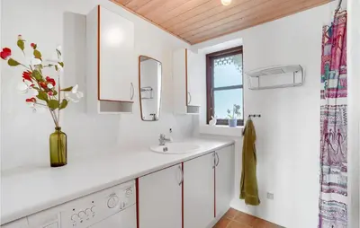a white bathroom with a sink and a vase of flowers at Holiday Home Strandlyst Vinderup Iv in Vinderup