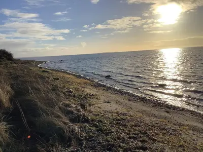 a beach with the sun shining on the water at 6 person holiday home in Vesløs-By Traum in Øsløs