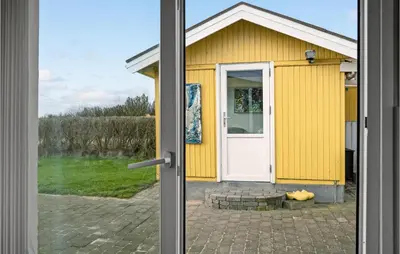 a view of a yellow house through a sliding door at 3 Bedroom Amazing Home In Spøttrup in Spottrup