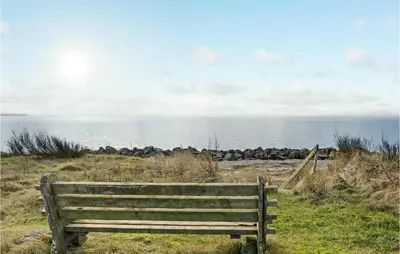 a wooden bench sitting on a hill overlooking the ocean at 3 Bedroom Amazing Home In Spøttrup in Spottrup