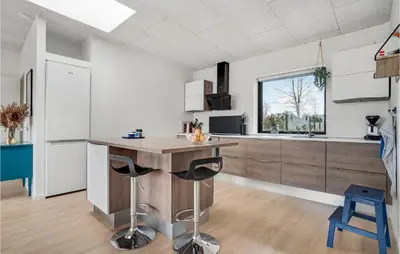 a kitchen with a wooden island with two bar stools at 4 Bedroom Gorgeous Home In Fur in Furland