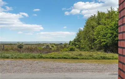 a brick wall next to a field with trees at 3 Bedroom Amazing Home In Vesløs in Øsløs