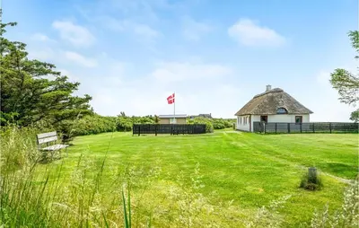 a grassy field with a building with a canadian flag at Gorgeous Home In Thyholm With Kitchen in Thyholm