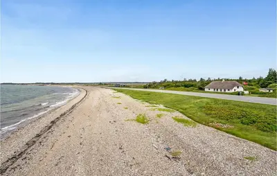an empty beach with a house and a road at Gorgeous Home In Thyholm With Kitchen in Thyholm