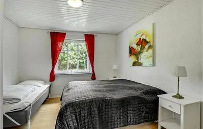 a bedroom with a bed and a window with red curtains at Amazing Home In Vestervig With Sauna in Vestervig