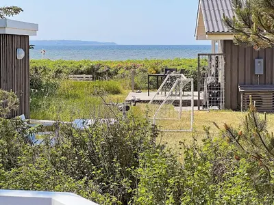 a yard with a playground with the ocean in the background at 7 person holiday home in Løgstør-By Traum in Løgsted