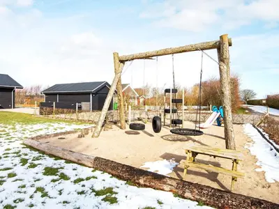 a swing set in a yard with snow at Modern Cottage with Spa - By Traum Ferienwohnungen in Vinderup