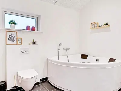 a white bathroom with a tub and a toilet at Modern Cottage with Spa - By Traum Ferienwohnungen in Vinderup