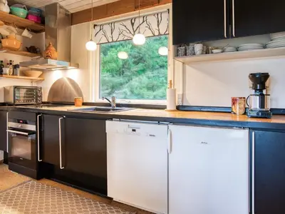 a kitchen with black and white appliances and a window at 6 person holiday home in Blokhus-By Traum in Blokhus