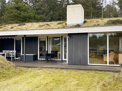 a house with a deck with a grass roof at 6 person holiday home in Blokhus-By Traum in Blokhus