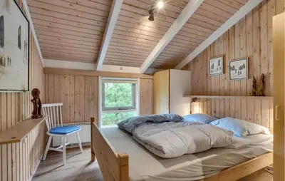 a large bed in a room with wooden walls at Gorgeous Home In Blokhus With Wifi in Blokhus