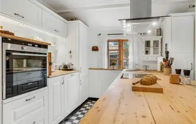 a kitchen with white cabinets and a wooden floor at 2 Bedroom Lovely Home In Højslev in Højslev