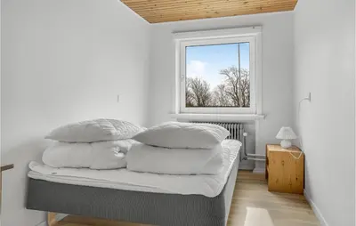 a bedroom with a bed with four pillows on it at 5 Bedroom Stunning Home In Hanstholm in Hanstholm
