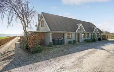 a house with a gambrel roof on a gravel driveway at Gorgeous Home In Øster Assels in Øster Assels