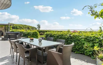 a patio with a table and chairs and a hedge at Gorgeous Home In Øster Assels in Øster Assels